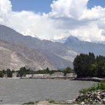 The Gilgit River, carrying muddy water from the mountains, reflects the seasonal changes and melting snow as it flows through the valley