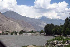 The Gilgit River, carrying muddy water from the mountains, reflects the seasonal changes and melting snow as it flows through the valley