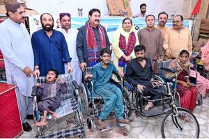 Chairman District Council Larkana Aijaz Ahmed Laghari distributing wheelchairs to disabled persons during a ceremony at the WAPDA Labor Hall