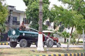 Workers of the Chaklala Cantonment Board sprinkle water on trees and plants in the green belt to protect them from the intense summer heat.