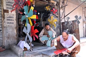 A worker is making room cooler fans at his workplace along the roadside in the city.