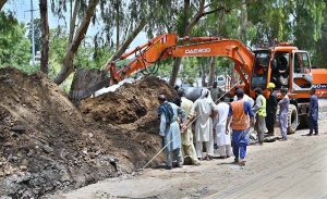 Labourers are busy digging place for laying sewerage pipeline near Khayaban-e-Sir Syed Service Road using heavy machinery.