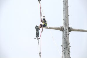 A WAPDA worker installs new power lines on a high electricity pole along Lathrar Road.