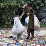 Gypsy youngsters searching valuables from garbage spreading at roadside