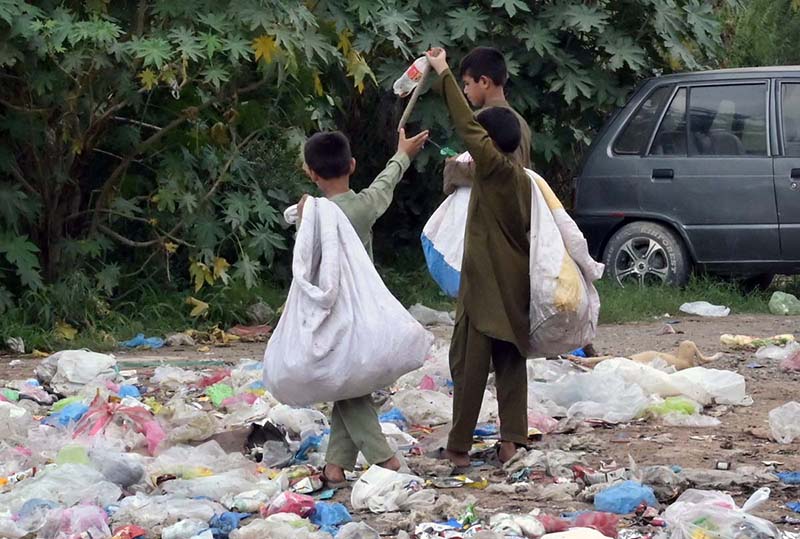 Gypsy youngsters searching valuables from garbage spreading at roadside