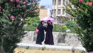 Girls on their way under cover of an umbrella to protect from direct sunlight during hot weather in the Federal Capital.