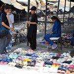 Vendors display footwear for sale amid the burnt ruins of H-9 weekly Bazaar, showing remarkable resilience as they resume trade following the devastating fire that gutted the market