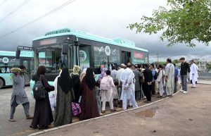 A large number of people are boarding an electric bus at Kana Pul.