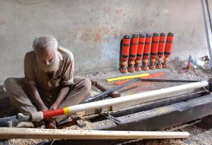 A carpenter busy in making part of a traditional bed (charpai) at his workplace.