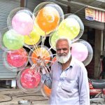 An elderly vendor displaying balloons to attract the customers at Khana Pull