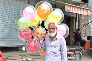 An elderly vendor displaying balloons to attract the customers at Khana Pull