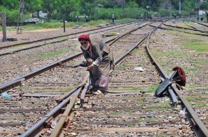 An elderly railway worker is manually operating a track switch at the railway yard to guide trains onto the designated rail line in the city