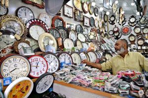 A vendor arranging and displaying wall clocks to attract the customers at weekly bazaar, Peshawar Morr