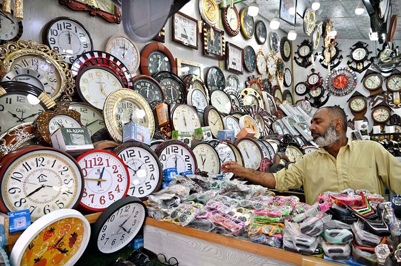A vendor arranging and displaying wall clocks to attract the customers at weekly bazaar, Peshawar Morr