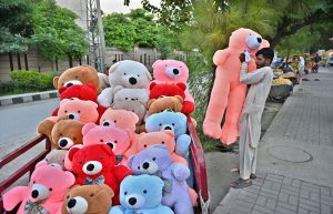 A vendor arranging and displaying huge teddy bears to attract the customers along Murree Road.