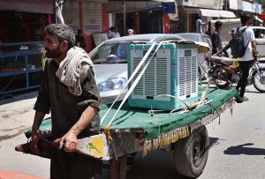 A laborer pulling handcart loaded with room-cooler for delivery to customer.