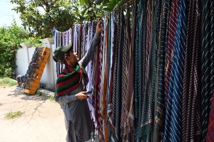 A young vendor displays and sells cotton handkerchiefs by the roadside during the severe summer heat
