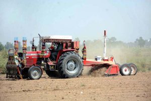 A farmer levels his field using a tractor to prepare it for the next crop.