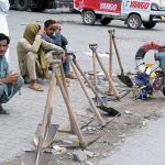 Labourers alongwith their tools sitting on roadside waiting for clients to be hired for work during morning time at Khanna Pul in Federal Capital
