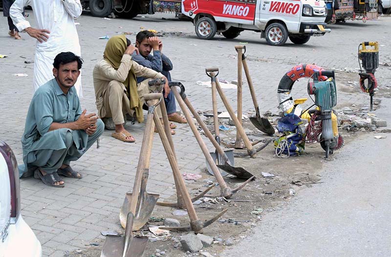 Labourers alongwith their tools sitting on roadside waiting for clients to be hired for work during morning time at Khanna Pul in Federal Capital