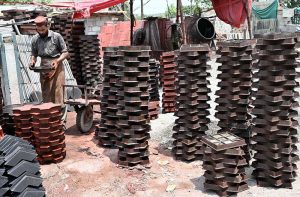 A worker is busy making and laying out tuff tiles to dry at his workplace during the hot weather in the city.