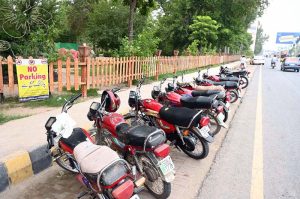 A large number of motorcycles parked under a 'No Parking' sign in front of the Botanical Garden.