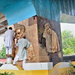 An artist gives finishing touches to a golden relief mural of the Founder of Pakistan, Quaid-e-Azam Muhammad Ali Jinnah on a pillar beneath the Kachehry Chowk flyover ahead of Independence Day celebrations in the city