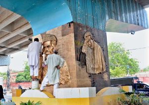 An artist gives finishing touches to a golden relief mural of the Founder of Pakistan, Quaid-e-Azam Muhammad Ali Jinnah on a pillar beneath the Kachehry Chowk flyover ahead of Independence Day celebrations in the city
