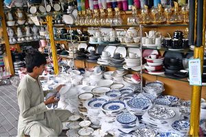 A vendor arranging and displaying wall clocks to attract the customers at weekly bazaar, Peshawar Morr