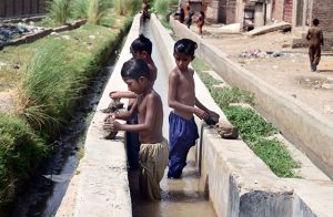 Children enjoying and making toys from clay after bathing on running tube well during hot weather in the city.