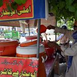 A vendor sells tamarind and plum juice by the roadside as people drink it to beat the intense summer heat