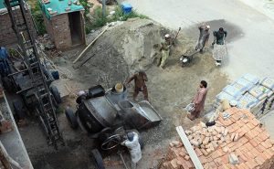 Construction workers lay and level fresh concrete on the rooftop of a building under construction. Wearing rubber boots, the labourers carefully spread and smooth the concrete over steel reinforcement bars as construction activity continues across the twin cities despite the ongoing monsoon season