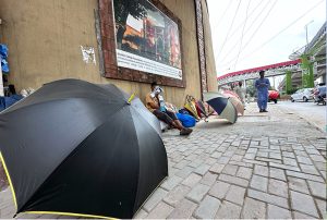 A vendor waits for customers while displaying umbrellas along a roadside at Marir Chowk.