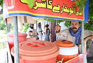 A vendor sells tamarind and plum juice by the roadside as people drink it to beat the intense summer heat