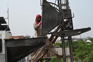 Construction workers lay and level fresh concrete on the rooftop of a building under construction. Wearing rubber boots, the labourers carefully spread and smooth the concrete over steel reinforcement bars as construction activity continues across the twin cities despite the ongoing monsoon season