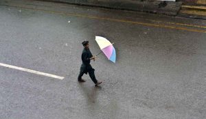 A youngster on the way carrying umbrella during rain that experienced the city.