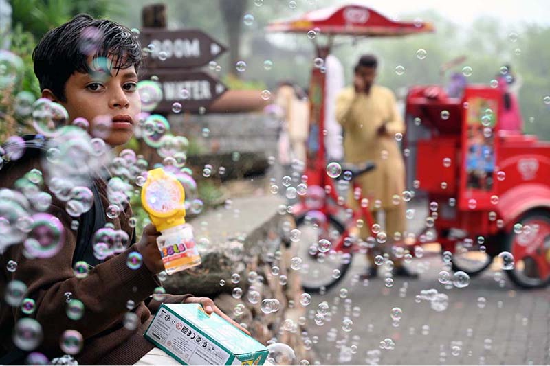 A young vendor is making bubbles with a bubble-making toy to attract children and sell the toy at the famous picnic point, Daman-e-Koh