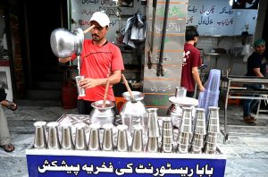A vendor preparing Lassi to attract customers at his roadside setup.