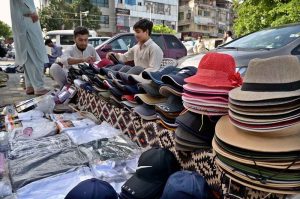 A vendor arranging and displaying caps to attract the customers at G-9 Markaz in Federal Capital.