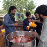 Volunteers distribute free chilled drink to citizens including children at a roadside