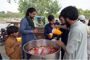 Volunteers distribute free chilled drink to citizens including children at a roadside