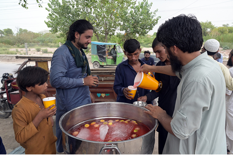 Volunteers distribute free chilled drink to citizens including children at a roadside