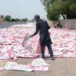 A worker spreads and arranges empty polypropylene sacks for drying under the sun along a roadside before they are reused for agricultural and commercial purposes in the city