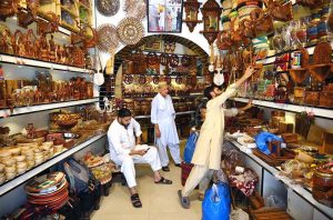 Customer selecting and purchasing wooden handmade decoration items from the handicraft shop at Namak Mandi Chowk.