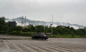 Low-lying clouds and mist blanket the Margalla Hills as a vehicle navigates through a rain-soaked road in Federal Capital following heavy monsoon rainfall
