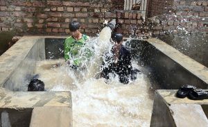 Youngsters enjoying bathing in the running tube-well to get relief from hot weather in the city.