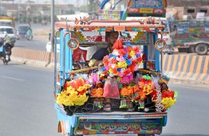 A vendor transports decorative artificial flowers on a three-wheeler for sale in different parts of the city.
