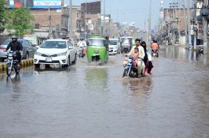 Vehicles pass through stagnant rainwater on a city road.
