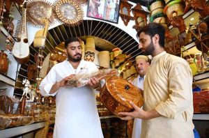 Customer selecting and purchasing wooden handmade decoration items from the handicraft shop at Namak Mandi Chowk.