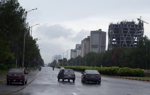 Low-lying clouds and mist blanket the Margalla Hills as a vehicle navigates through a rain-soaked road in Federal Capital following heavy monsoon rainfall